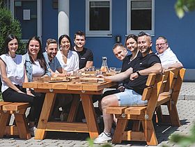 Einige Mitarbeiter der Firma Meltem sitzen an einem großen Tisch und essen Pizza