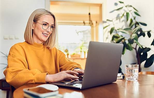 eine Frau arbeitet in ihrem Wohnzimmer am Laptop