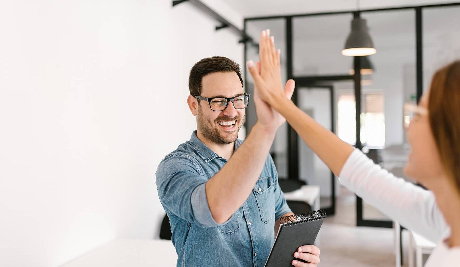 ein Mann und eine Frau geben sich im Büro ein Highfive