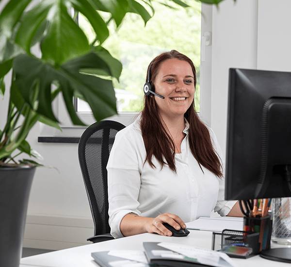 Frau mit Headset sitzt vor ihrem Bildschirm