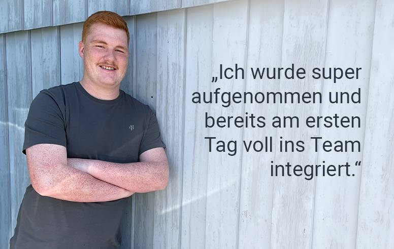 Ein Mitarbeiter vor einer blauen Holzwand